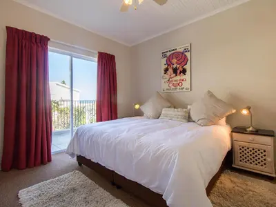 a bedroom with a bed and a large window at 'Die Braaihuis'- sleeps 6, Large Veranda, Sea Views, Central and Fabulous! in Gordonʼs Bay