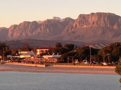 a view of a beach with mountains in the background at 'Die Braaihuis'- sleeps 6, Large Veranda, Sea Views, Central and Fabulous! in Gordonʼs Bay