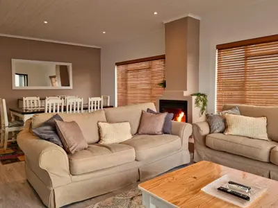a living room with two couches and a fireplace at 'Die Braaihuis'- sleeps 6, Large Veranda, Sea Views, Central and Fabulous! in Gordonʼs Bay