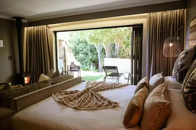 a large bed in a room with a large window at Silver Forest Boutique Hotel and Spa in Somerset West