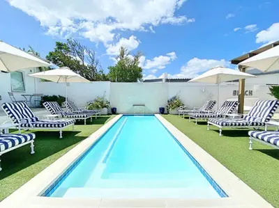 a swimming pool with lounge chairs and umbrellas at One Marine Drive Boutique Hotel & Spa by The Living Journey Collection in Hermanus
