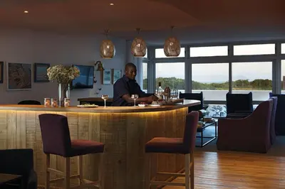 a man sitting at a bar in a restaurant at One Marine Drive Boutique Hotel & Spa by The Living Journey Collection in Hermanus