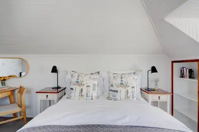 a bedroom with a white bed with two tables and two lamps at Beautiful Abalone in Hermanus
