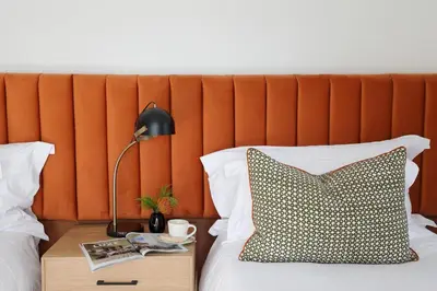 a bed with a table with a pillow and a lamp at Twice Central Guest House in Stellenbosch
