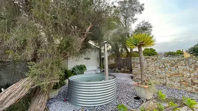 a barrel in a garden with a tree at Pashasha Beach House and Hot Tub in Hermanus