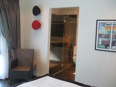 a bedroom with a shower and a chair in a room at KaapsePracht Bed & Breakfast in Somerset West