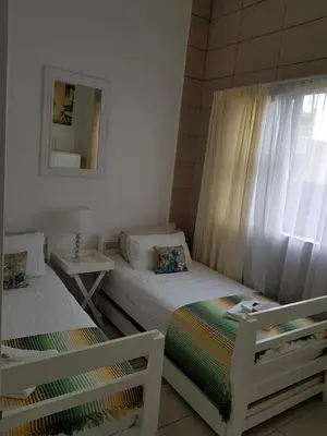 a bedroom with two beds and a window with a mirror at Stukkie Cottage in Hermanus