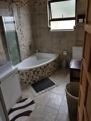 a bathroom with a bath tub and a window at Stukkie Cottage in Hermanus
