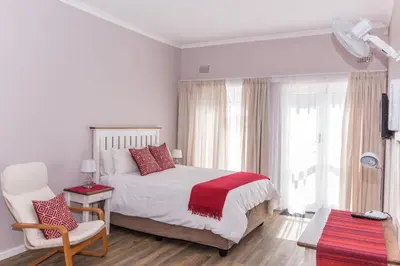 a white bedroom with a bed and a chair at 10 Windell Self Catering Accommodation in Durbanville