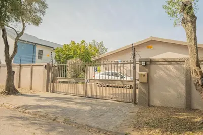 a fence in front of a house with a car at 10 Windell Self Catering Accommodation in Durbanville