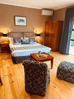 a bedroom with a bed and a table and a chair at Vine Guesthouse in Stellenbosch