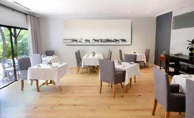 a dining room with white tables and chairs and a piano at Vine Guesthouse in Stellenbosch