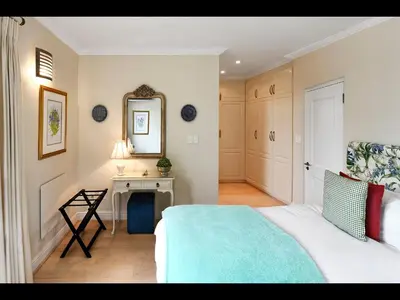 a bedroom with a bed and a table and a mirror at 10 Villefranche in Franschhoek