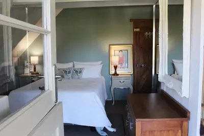 a bedroom with a white bed and a mirror at Kimi's Cottage in Simondium
