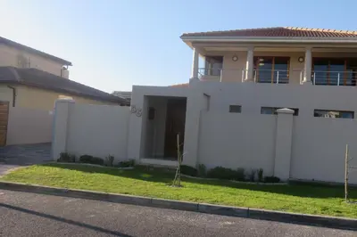 a white house with a fence in front of it at Waves Echo in Bloubergstrand