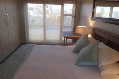 a bedroom with a bed with pillows and a window at Waves Echo in Bloubergstrand