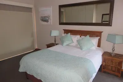 a bedroom with a large white bed with a mirror at Waves Echo in Bloubergstrand