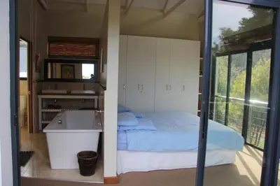 a bedroom with a bed and a tub and a sink at Riverside 18 in Hermanus