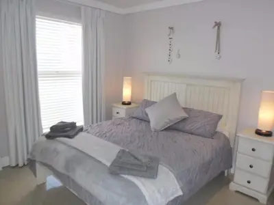 a bedroom with a bed with two night stands and two lamps at Whale Rock 54 in Hermanus