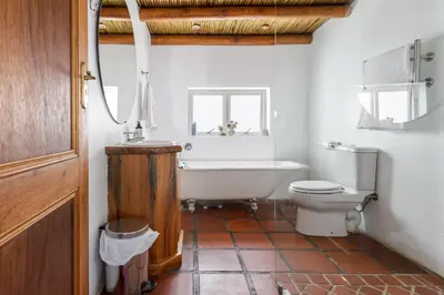 a bathroom with a tub and a toilet and a sink at Strand Beach Lodge in Strand