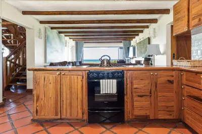 a kitchen with wooden cabinets and a black stove at Strand Beach Lodge in Strand