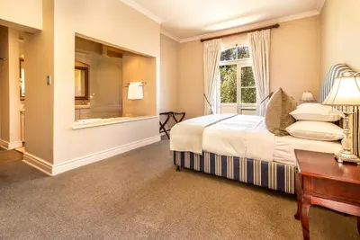 a bedroom with a bed and a window and a desk at L'ermitage - Franschhoek Chateau & Villas in Franschhoek