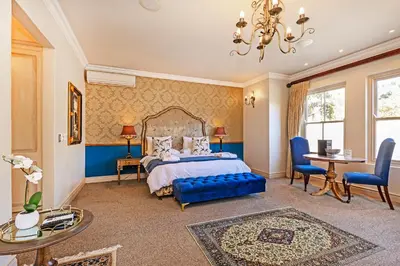a bedroom with a bed and a table and chairs at L'ermitage - Franschhoek Chateau & Villas in Franschhoek