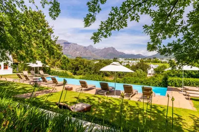 a pool with chairs and umbrellas in a yard at De Zalze Lodge in Stellenbosch