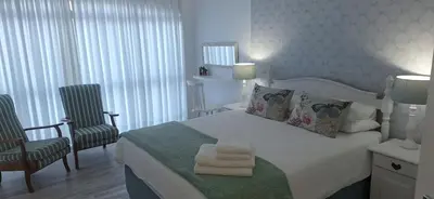 a bedroom with a bed with two chairs and two towels at Sit-en-Kyk in Hermanus