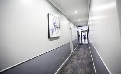 a hallway with white walls and a painting on the wall at New National Hotel and Conference in Parow
