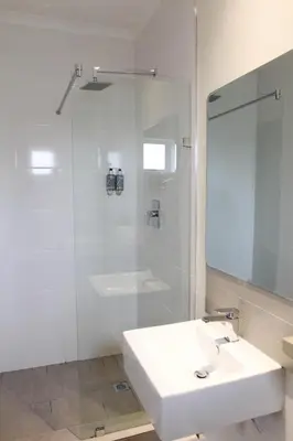 a white bathroom with a sink and a shower at New National Hotel and Conference in Parow
