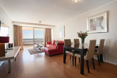 a living room with a table and a red couch at Lagoon Beach 136A by CTHA in Cape Town