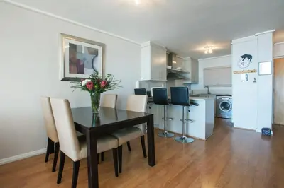 a dining room table with chairs and a vase of flowers at Lagoon Beach 136A by CTHA in Cape Town