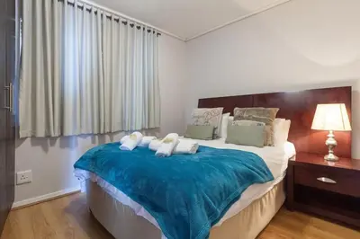 a bedroom with a large bed with a blue blanket at Lagoon Beach 136A by CTHA in Cape Town