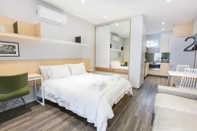 a bedroom with a bed and a desk and a kitchen at Laanhof Studios in Stellenbosch