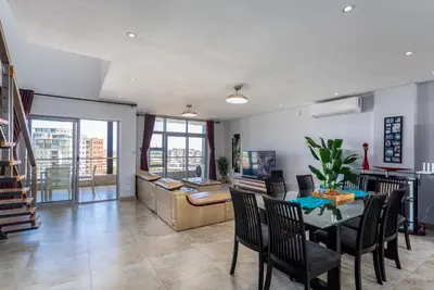a dining room with a table and chairs and a desk at Knightsbridge Luxury Suite in Century City by CTHA in Cape Town