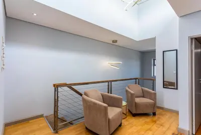 a living room with two chairs and a staircase at Knightsbridge Luxury Suite in Century City by CTHA in Cape Town