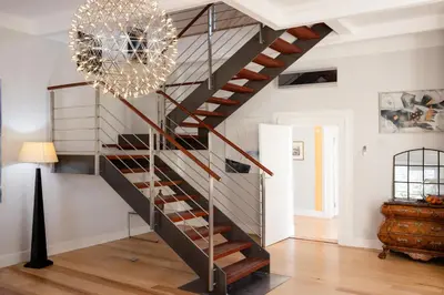 a metal staircase in a living room with a chandelier at Allèe Bleue Wine Estate in Simondium