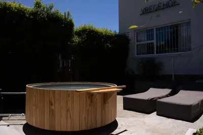 a wooden tub sitting in a yard next to a building at Avemore Vredehof No 2 - full Backup Power in Stellenbosch