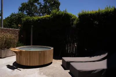 a wooden hot tub in a yard with two stools at Avemore Vredehof No 2 - full Backup Power in Stellenbosch