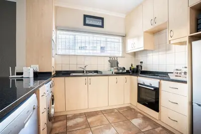 a kitchen with wooden cabinets and black counter tops at Avemore Vredehof No 2 - full Backup Power in Stellenbosch