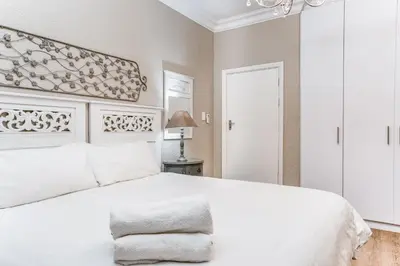 a bedroom with a white bed and a chandelier at Avemore Vredehof No 2 - full Backup Power in Stellenbosch