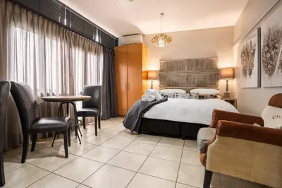 a hotel room with a bed and a table and chairs at Avemore Eikehoff No 24 full back up power in Stellenbosch