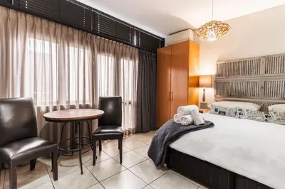 a hotel room with a bed and a table and chairs at Avemore Eikehoff No 24 full back up power in Stellenbosch