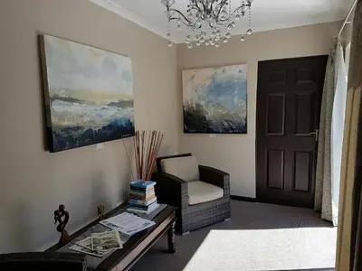 a living room with a chair and a table and a chandelier at Seaside Hermanus Guest Room in Hermanus