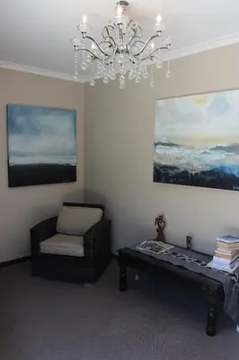 a living room with a chair and a chandelier at Seaside Hermanus Guest Room in Hermanus