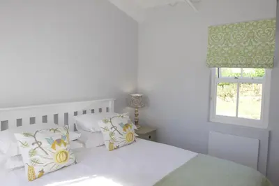 a bedroom with a white bed with pillows and a window at Paul Wallace Wines & Cottages in Elgin