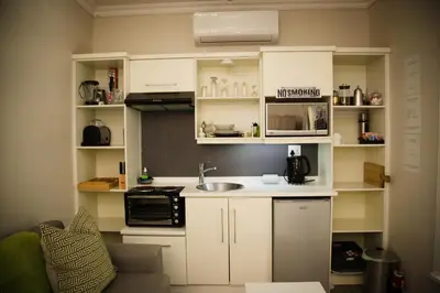 a small kitchen with white cabinets and a sink at Afrika-Pearl in Paarl