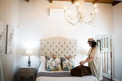 a man standing next to a bed in a room at Afrika-Pearl in Paarl