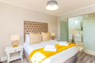 a bedroom with a large white bed and a bathroom at Quayside 301 by CTHA in Cape Town